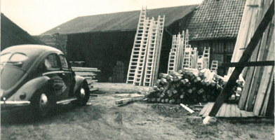 Foto histórica do grupo DOLLE, com veículos da época e estruturas industriais.