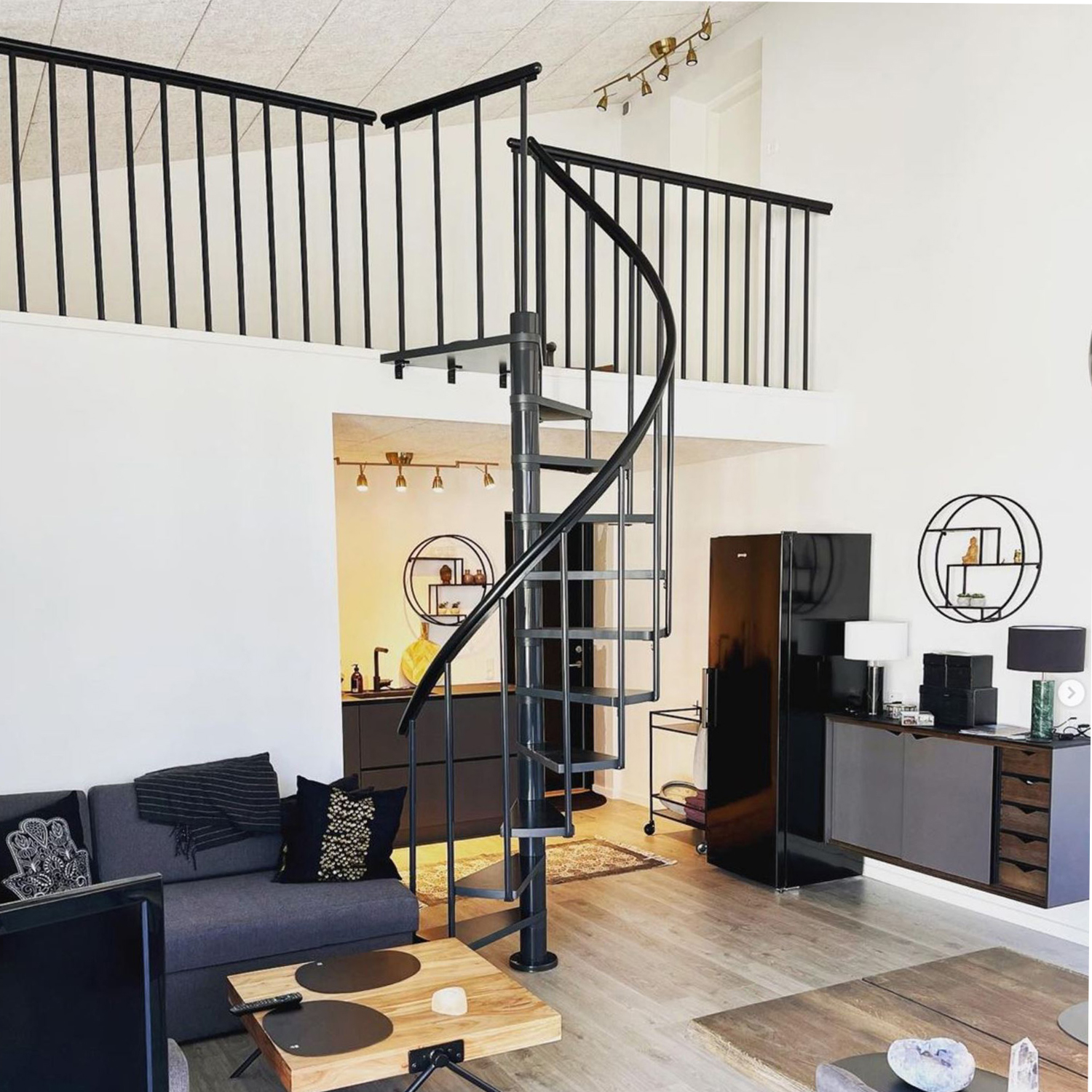 Escada espiral em metal preto em uma sala de estar contemporânea com decoração moderna.